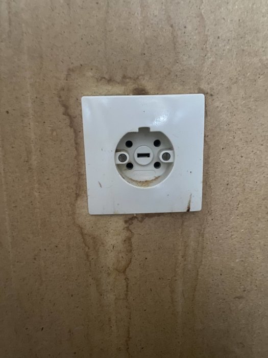 Ett smutsigt, vit vägguttag på en marmorerad bakgrund.