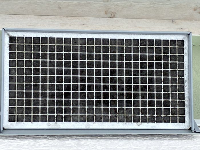 Smutsig luftkonditioneringsfilter inramad med aluminium, i behov av rengöring eller byte.