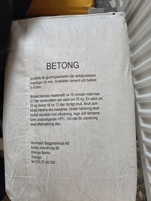 En sliten betongsäck med instruktioner, användningsområde och varningsinformation på svenska, från Hornbach Byggmarknad AB.