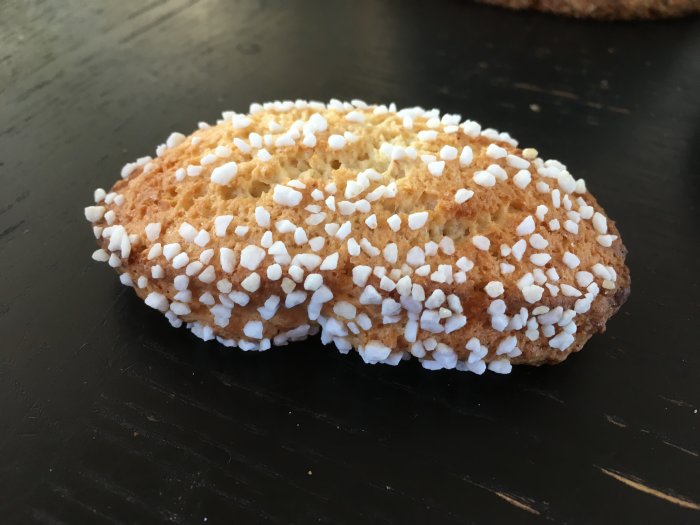 Ett svenskt fikabröd, kallat "sockerkaka", täckt av pärlsocker på en mörk yta.