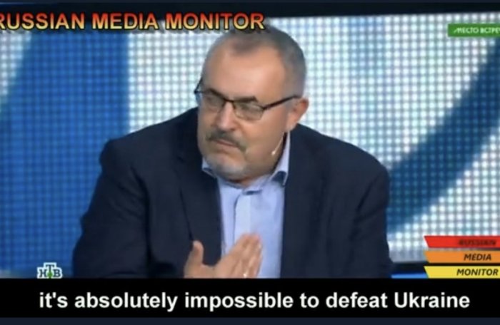 Man i kostym talar i TV, undertexter, "omöjligt att besegra Ukraina", "RUSSIAN MEDIA MONITOR" grafik.