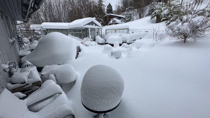 Vinterträdgård och möbler täckta av tjockt lager snö.