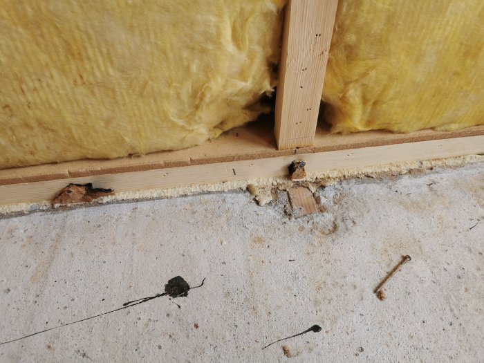 Isolering i vägg, skada på trä, betonggolv, spik, trasiga träbitar, byggnadsskada.