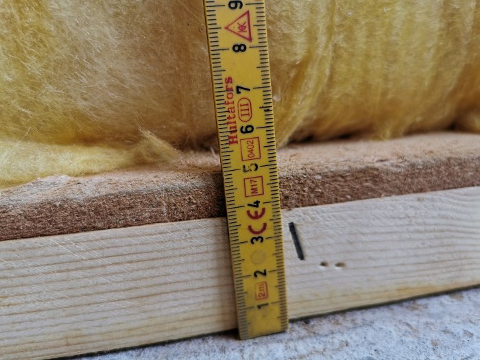 Måttband mot isolering och trä, mätning av konstruktionsmaterial.