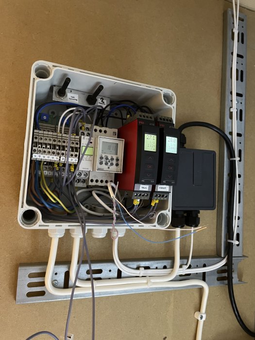 Elektriskt styrsystem med kablar, reläer och gränssnitt, monterat på vägg, oorganiserad, industrianläggning.
