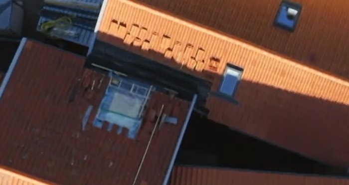 Flygbild av byggnad med takfönster och öppen taklucka i skymningen.