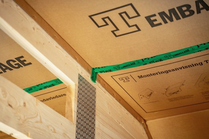 Brunt kartongmaterial, trälister, grönt tejpband, text, symboler, monteringsanvisningar. Inredning eller byggprojekt.