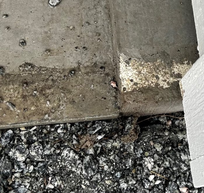 Betongplattor och asfalt möter, med slitage och smuts; detaljer för underhåll eller renovering synliga.
