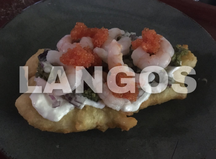 Langos med räkor, rödlök, gräddfilsås, och röd kaviar på svart tallrik.