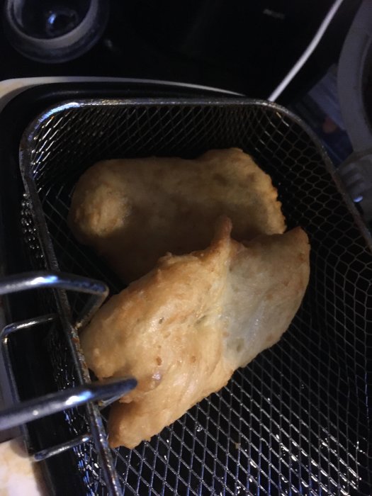 Friterade matobjekt i en korg mot en mörk bakgrund.