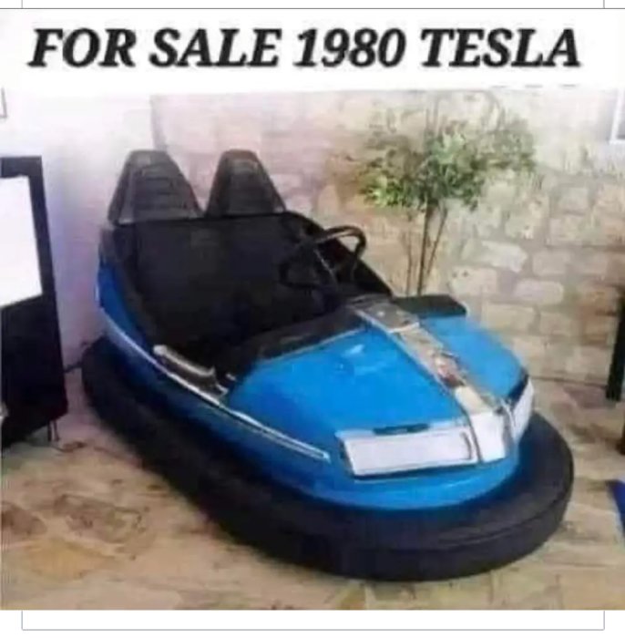 Bumperbil modifierad för att likna en Tesla, humoristisk skylt annonserar "1980 Tesla" till salu.