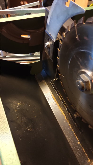 Industriell utrustning med cirkulärt sågblad, troligen en såg för trä eller metall, verkstadsmiljö.