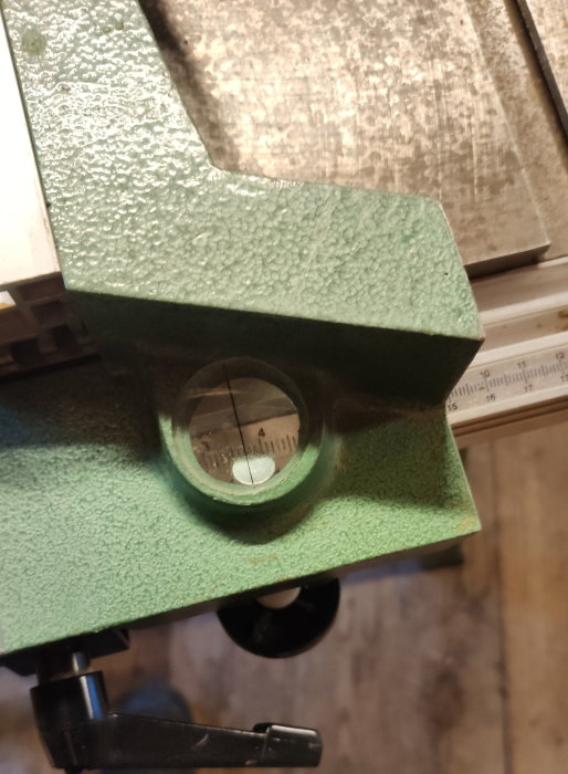 Vattenpass med bubbla inom markerade linjer, grönt, monterat på en yta, verktyg för precision.