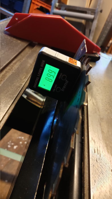 Digital vinkelhitta på cirkelsågsblad vid sågbord. Bakgrund med verktyg. Mäter bladets lutning.