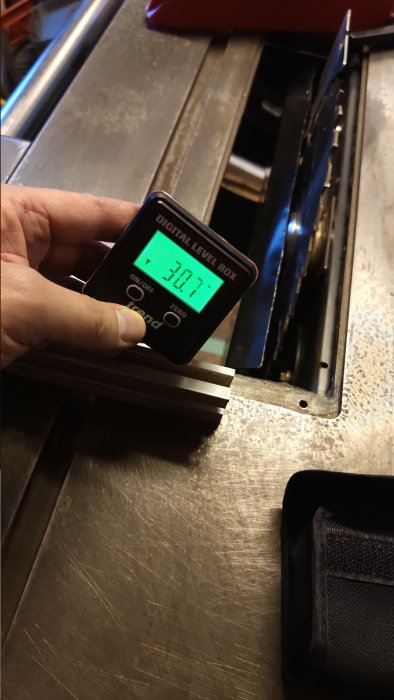 Digital nivåmätare visar 0,1°, används på metallisk yta, hand håller instrumentet, mätverktyg för precision.