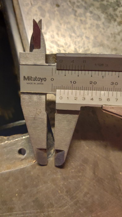 Mitutoyo skjutmått i förgrunden, mäter ett objekt, precisionstillverkningsverktyg, made in Japan, närbild.
