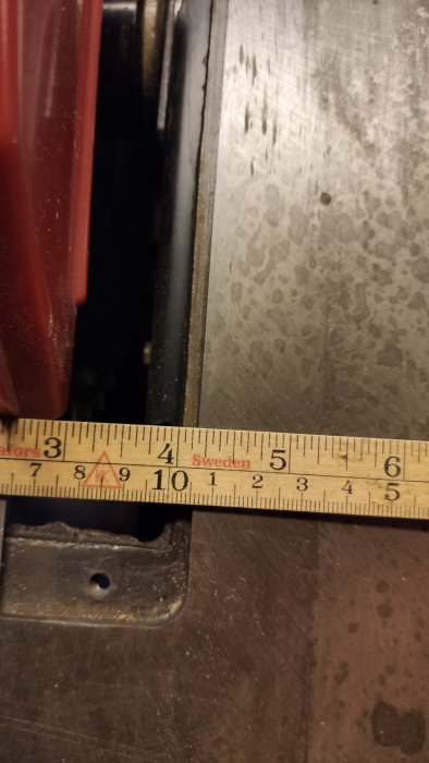 Närbild på mätverktyg (tumstock) vid sidan av metallföremål, mätningskontext, använt verktyg, fokus på skala.