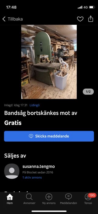 Stor grön vertikal bandsåg bortskänkes, verktyg och trä bakom, inuti snickarverkstad.