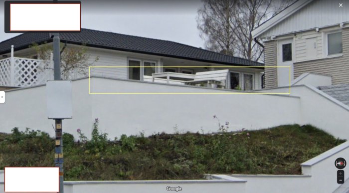 Vit villa med svart tak, terrass, på en sluttning, med vita staket. Bilden är tagen från Google Street View.