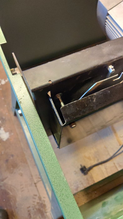 Industriellt objekt, metallram, svetsad konstruktion, grönt stöd, kabel, otydlig miljö, konstruktion eller maskindel.