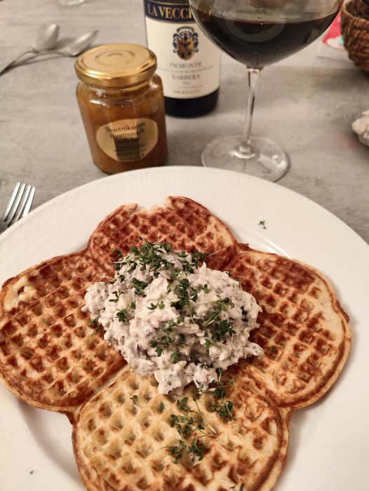 Våfflor med röra och timjan, svartkråkans hovmästarsås, rött vin, elegant måltid, middagstillbehör i bakgrunden.