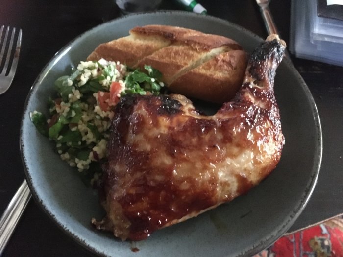 Grillad kycklinglår, tabbouleh-sallad och rostat bröd på en tallrik.