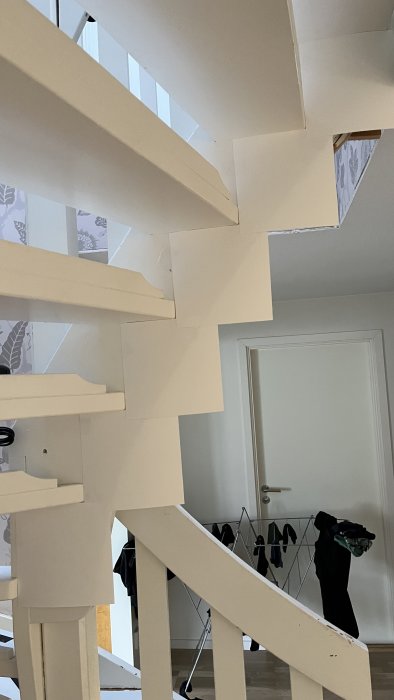 Modern trappa i hemmiljö med vit målning, design med synliga trappsteg och skarpa vinklar.