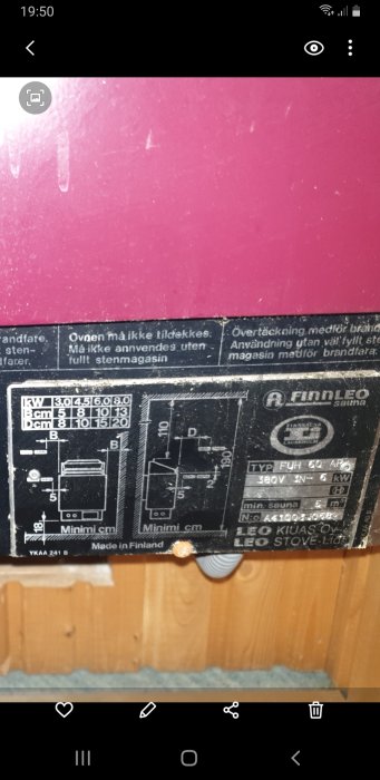 Instruktionsmärkning på en bastuugn, med tekniska specifikationer och säkerhetsföreskrifter, taget inomhus, Finland.