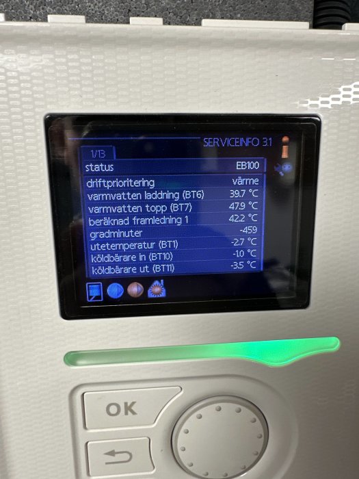Digital skärm visar temperaturvärden för värmeanläggning, driftinformation, omgivna knappar och statusindikator lyser grönt.