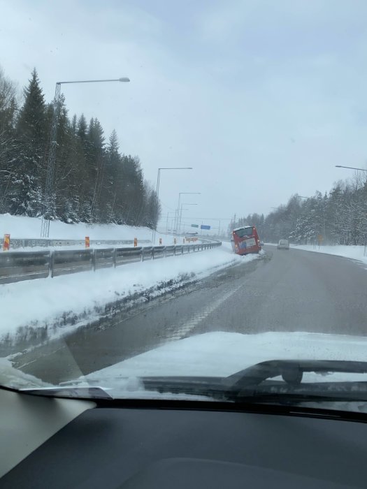 Lastbil välte på snöig väg, trafikstockning uppstår, potentiellt riskabla förhållanden, foton taget från bil.