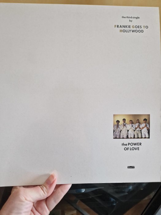 Ett skivomslag för "Frankie Goes to Hollywood", med titeln "the POWER OF LOVE", minimalistisk design, någon håller i det.