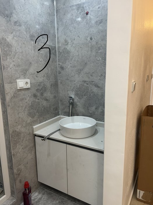 Modernt badrum, grå kakelväggar, vit handfat på skåp, duschkabin, ren design, byggarbetsmaterial, siffra tre på glas.