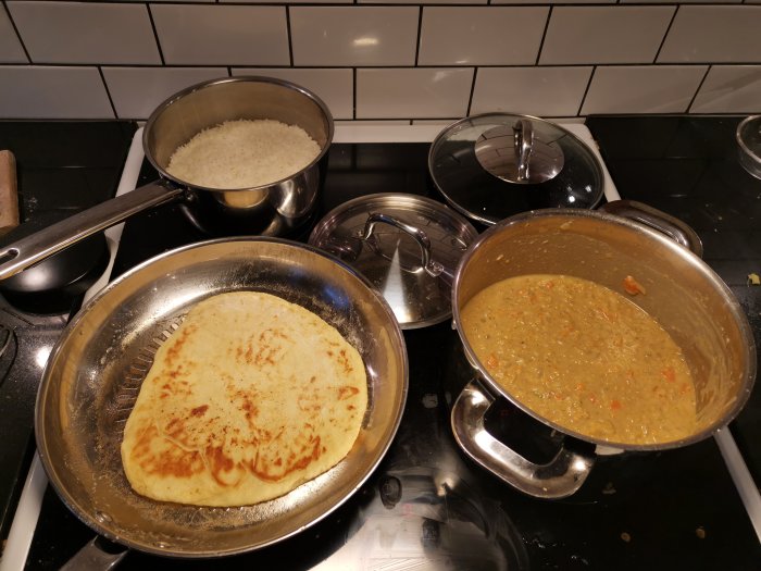 Kokplatta med ris, bröd och gryta. Matlagning hemma. Spis och köksredskap.