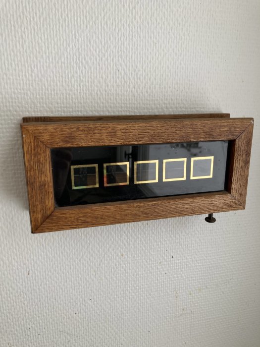 Väggmonterad flippklocka i träram, vit vägg, retro design, tiden synlig, analog digital hybrid.