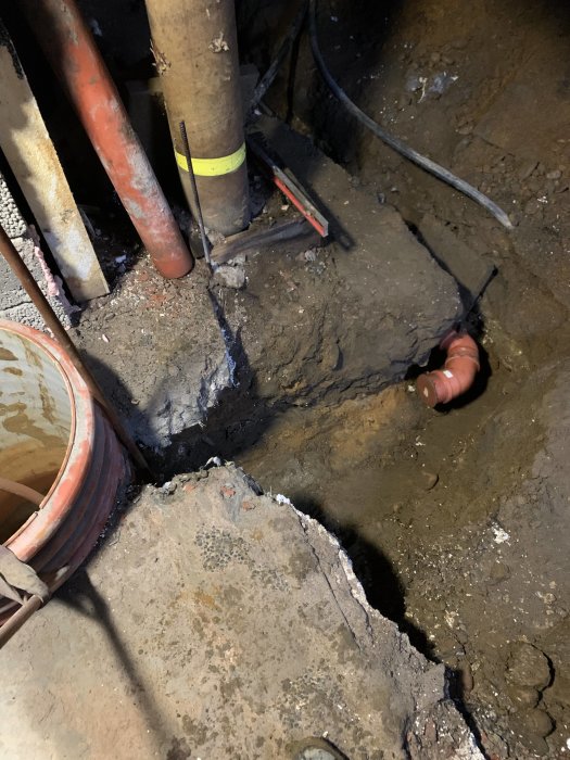 Grop i mark med rör och kablar, troligen underhålls- eller reparationsarbete pågår.