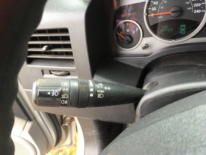 Bilens instrumentpanel, blinkerspaken, vindrutetorkarkontroll, fartmätare, bränslemätare, dörröppningsvarning. Luftventil i förgrunden.