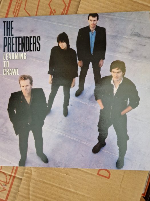 Skivomslag, "The Pretenders - Learning to Crawl", fyra bandmedlemmar, stående, minimalistisk och stilren design.