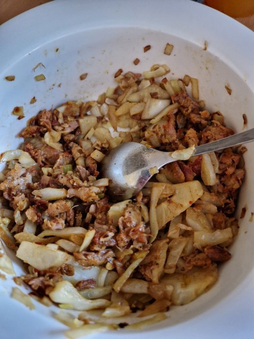 En skål med en röra av hackad mat, troligen en blandning av krossat kött och hackad lök.