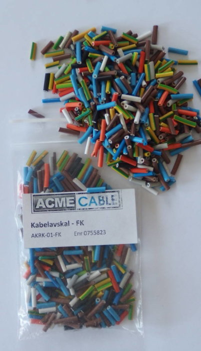 Färgglada krympslangar utspridda och inpackade, för kabelmärkning, med etikett märkt "ACME CABLE Kabelavskal - FK".