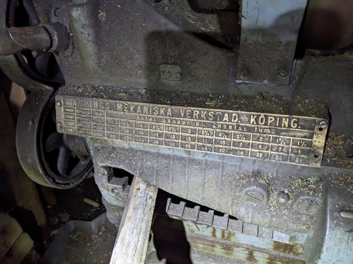 Äldre maskin med mässingsskylt. På skylten: "KÖPINGS MEKANISKA VERKSTAD, KÖPING". Tabell med tekniska specifikationer.