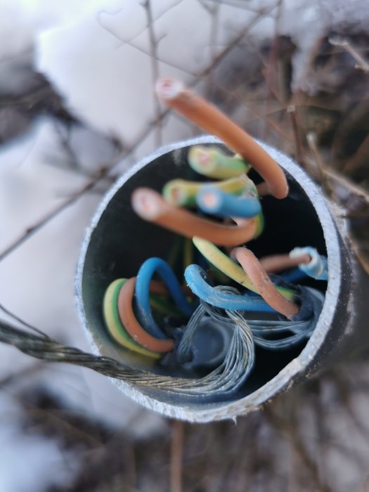 Avskalade elkablar i rörstickning ut, detaljbild, utomhus med synlig vintermiljö i bakgrunden.