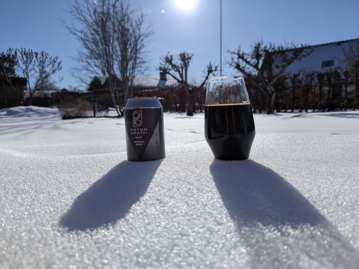 Ölburk och glas på snötäckt yta med solsken och skuggor, vinterdag utomhus.