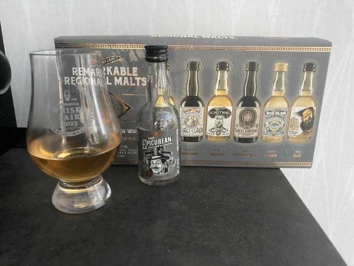 Whiskyprovsmakningsset med sex små flaskor och ett glas halvfyllt med whisky.