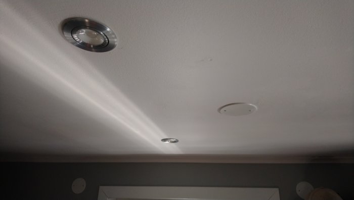 Tak med infällda spotlights och synligt ljusstråle från en av dem.