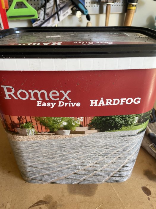 Förpackning Romex Easy Drive, röd etikett, plastbehållare, på en verkstadsbänk.