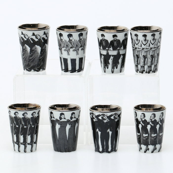 Åtta snapsglas med historiska bilder av människor, placerade på tre nivåer mot vit bakgrund.