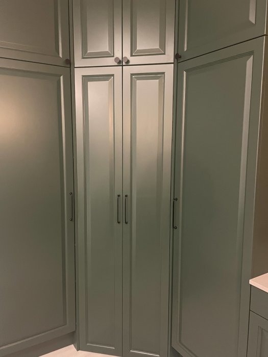 Inbyggda skåp med paneler och handtag, ljusgrön färg, minimalistisk design, inomhus, modern inredning.
