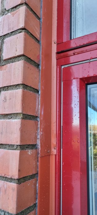Röd fönsterkarm på tegelvägg, vattendroppar, arkitektur detalj, externt, dagsljus, närbild.