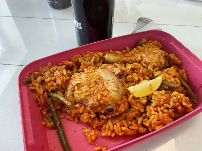 Matlåda med ris, kyckling, gröna bönor, citronklyfta. Röd plastbehållare. Matförberedelse eller lunch.