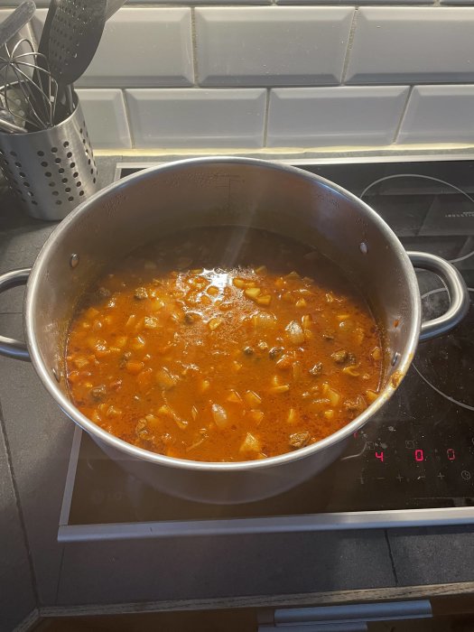 En gryta med mat står på en induktionshäll i ett kök.